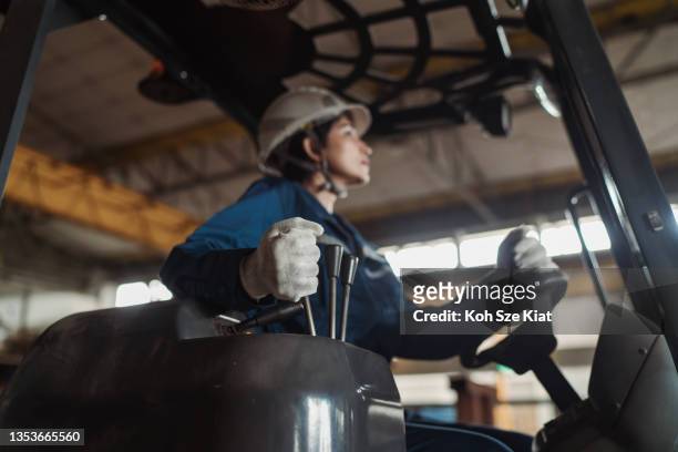 baugewerbe - asiatische facharbeiterin fährt rückwärts einen gabelstapler - female driving stock-fotos und bilder