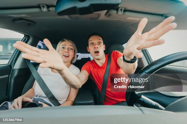 front view portrait of scared driver and passenger driving a car in a car accident - screaming happy in car stock-fotos und bilder