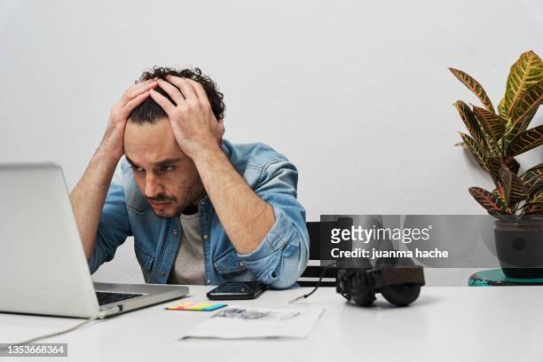 man having a stressful time while working with a laptop at home. - burn out stock-fotos und bilder
