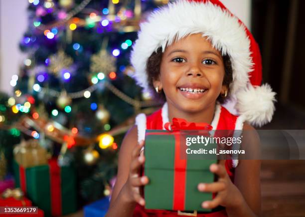 niño afroamericano emocionado sosteniendo un regalo de navidad envuelto - giving a girl head fotografías e imágenes de stock