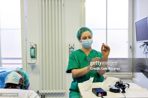 ophthalmologist wearing surgical gloves for operating a woman patient in eye hospital - operating gown stock pictures, royalty-free photos & images