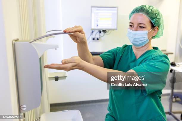 eye surgeon sanitizing her hands before surgery in operating room - doctor scrubs stock pictures, royalty-free photos & images