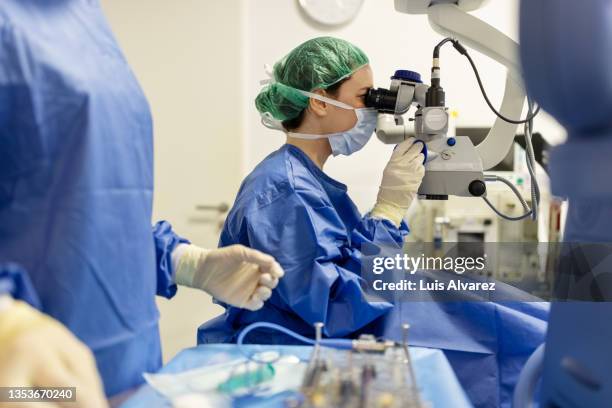 professional ophthalmologist performs eye surgery with a microscope - intervento chirurgico foto e immagini stock