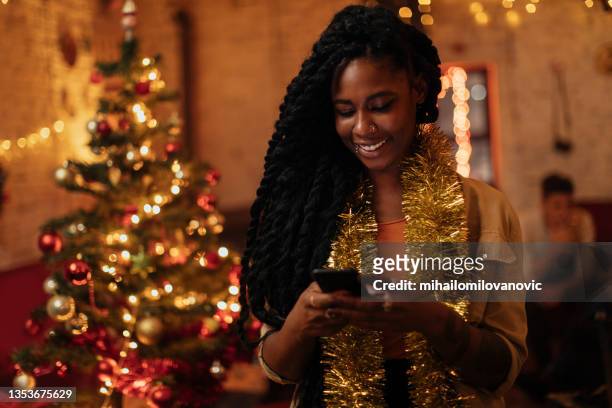 texting her friends and family for christmas - african ethnicity christmas stock pictures, royalty-free photos & images