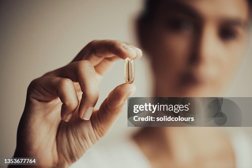Frau, die eine Vitaminkapsel zeigt Frau, die eine Vitaminkapsel zeigt