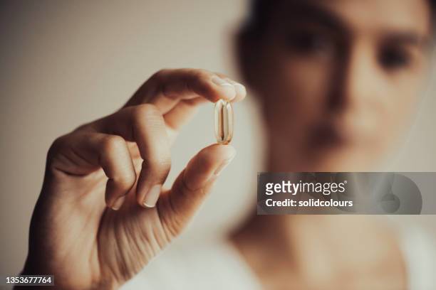 woman showing a vitamin capsule - vitamin d stock pictures, royalty-free photos & images