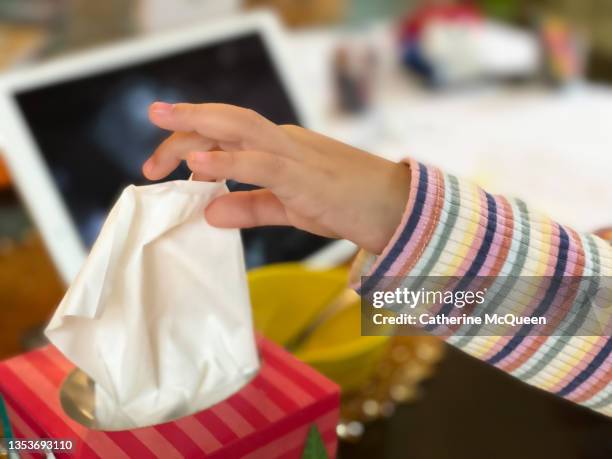 mixed-race young girl reaches for a tissue during online school at home while using digital tablet - box of tissues stock pictures, royalty-free photos & images