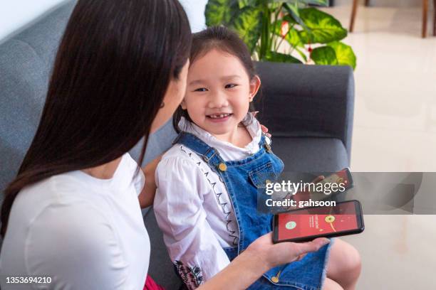 mother giving her daughter digital red envelope at chinese new year - receiving card stock pictures, royalty-free photos & images