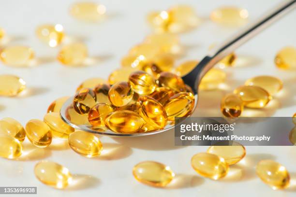 food supplement omega 3 in a spoon, medical supplements and vitamins d - huile de foie de morue photos et images de collection