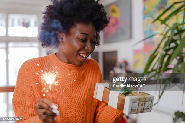 young woman holding christmas present and new year sparkler - new year gifts imagens e fotografias de stock