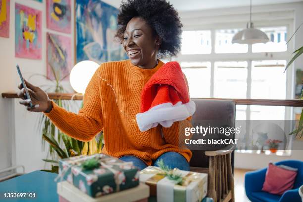 mujer joven sosteniendo el sombrero de papá noel y tomándose una selfie en casa - cat with red hat fotografías e imágenes de stock