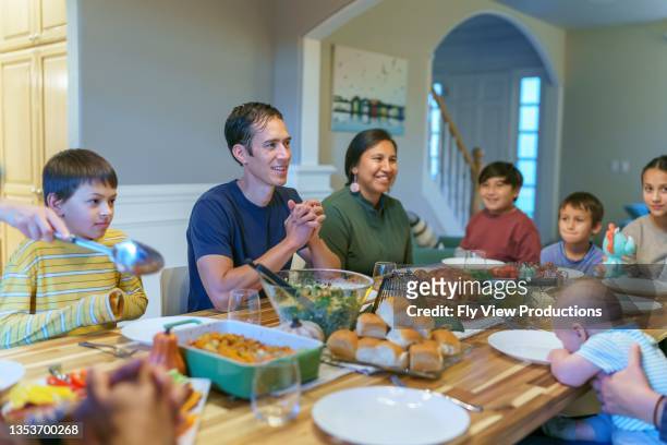 multi-ethnic group of family and friends celebrating thanksgiving together - indian family dinner table stock pictures, royalty-free photos & images
