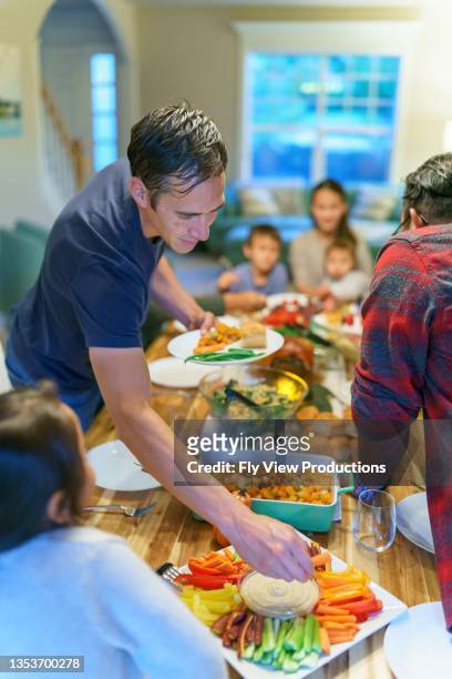 friends and family serving each other during holiday meal together - indian family dinner table stock pictures, royalty-free photos & images