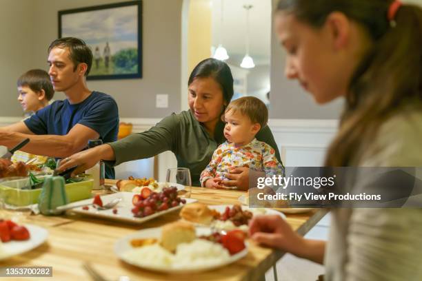 family eating together at holiday table - winter baby stock pictures, royalty-free photos & images