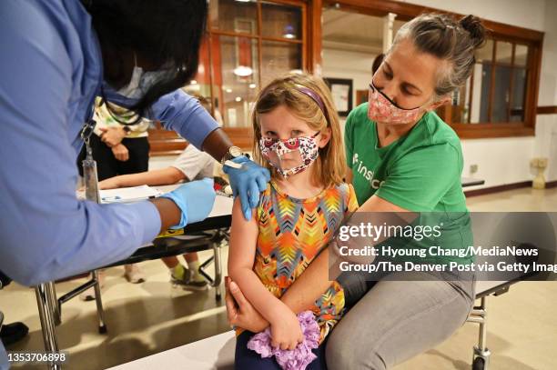 Camden VanBuskirk gets her first COVID-19 vaccine shot from medical assistant Yaa Prempeh, left, with her mother Monica, right, at West High School...