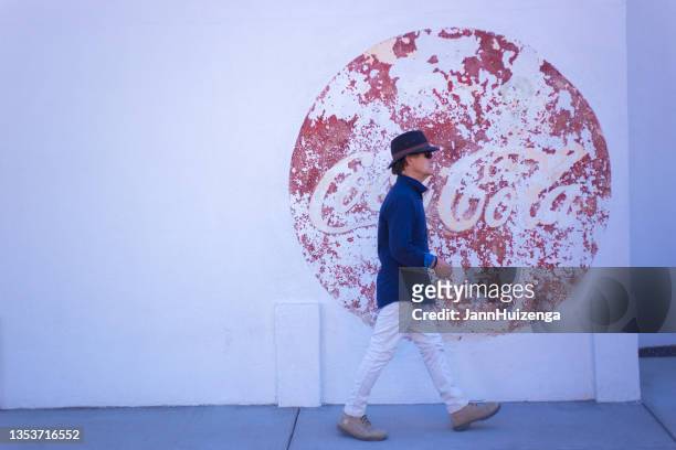 pedestrian walking past vintage coke ad in downtown marfa - pepsi centre stock pictures, royalty-free photos & images
