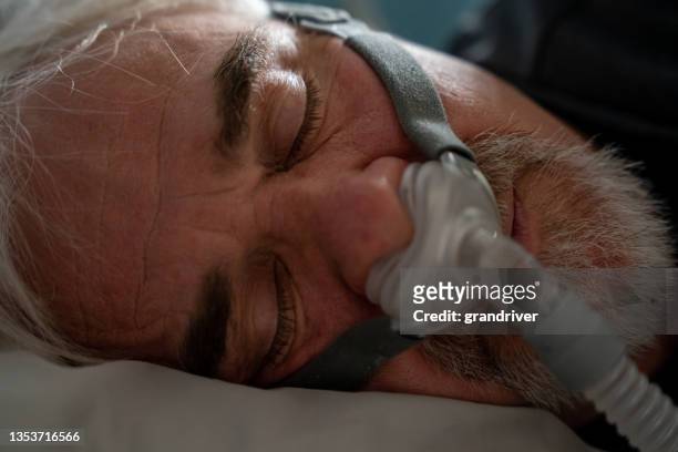 mature man sleeping with a cpap (continuous positive airway pressure) machine after being diagnosed with sleep apnea - respiratory failure stock pictures, royalty-free photos & images