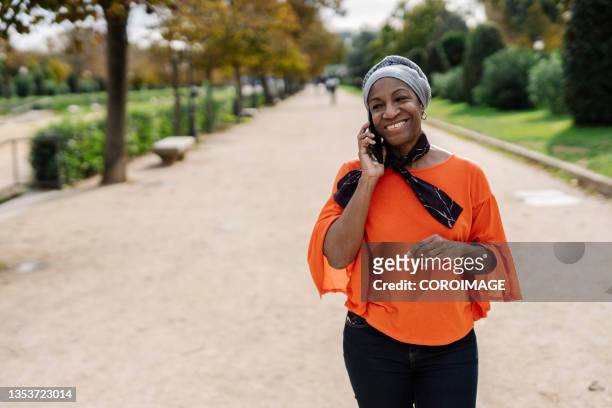black woman talking on the phone while walking outdoors in a park. - african american couple walking park ストックフォトと画像