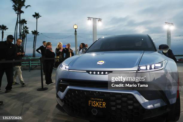 People gather and take pictures after the Fisker Ocean all-electric SUV was revealed at Manhattan Beach Pier on November 16, 2021 in Manhattan Beach,...
