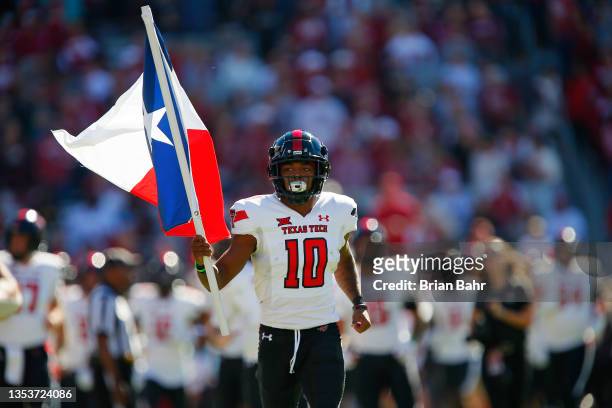 Wide receiver Kaylon Geiger Sr. #10 of the Texas Tech Red Raiders carries the Texas flag onto the field for a game against the Oklahoma Sooners at...
