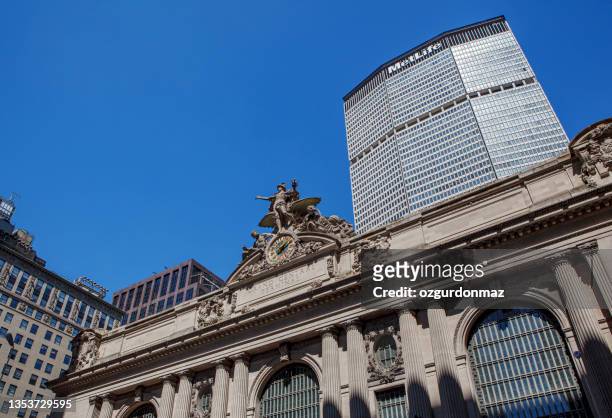 vista de ángulo bajo de sculptures y el reloj tiffany en la fachada exterior de grand central station, con el edificio metlife al fondo - metalife fotografías e imágenes de stock