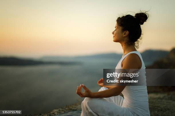 woman exercising yoga on a hill above the sea. - breathe stock pictures, royalty-free photos & images