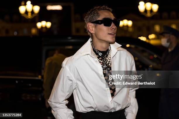 Evan Mock wears black sunglasses, a black fishnet / mesh tank-top, pearls necklaces, a gold large chain with teddy beard large pendant necklace from...