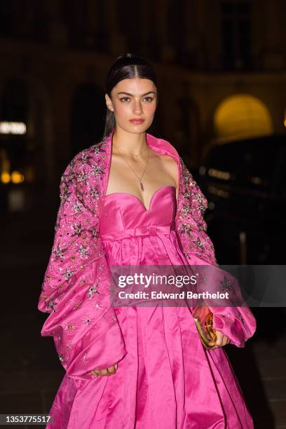 Zoia Mossour wears, gold chain with diamonds pendant necklaces from Messika, a shiny pink silk heart neck / shoulder-off / ruffled puffy knees dress,...