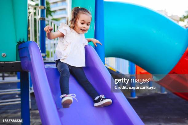 a 2-3 year old girl who slides off the slide is very happy, positive emotion - children's slide stock pictures, royalty-free photos & images