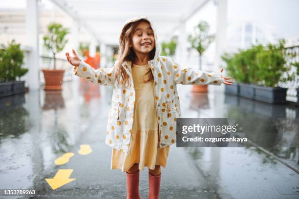 glückliches kleines mädchen, das auf dem regenstockfoto lächelt - girls in wet dresses stock-fotos und bilder