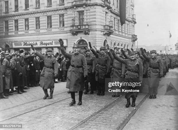 Austrian troops give the Nazi salute as they parade through the streets of Linz after the German Fuhrer and Chancellor Adolf Hitler had proclaimed...