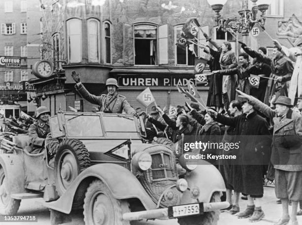 Austrian citizens celebrate by giving the Nazi salute as German 2nd SS Panzer Division "Das Reich" troops drive through the streets of Salzburg in a...