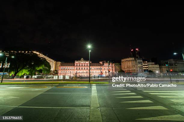 view of traffic driving on street with government building casa rosada in background - casa rosada stock pictures, royalty-free photos & images