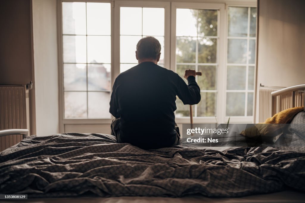 A lonely man is sitting on the bed