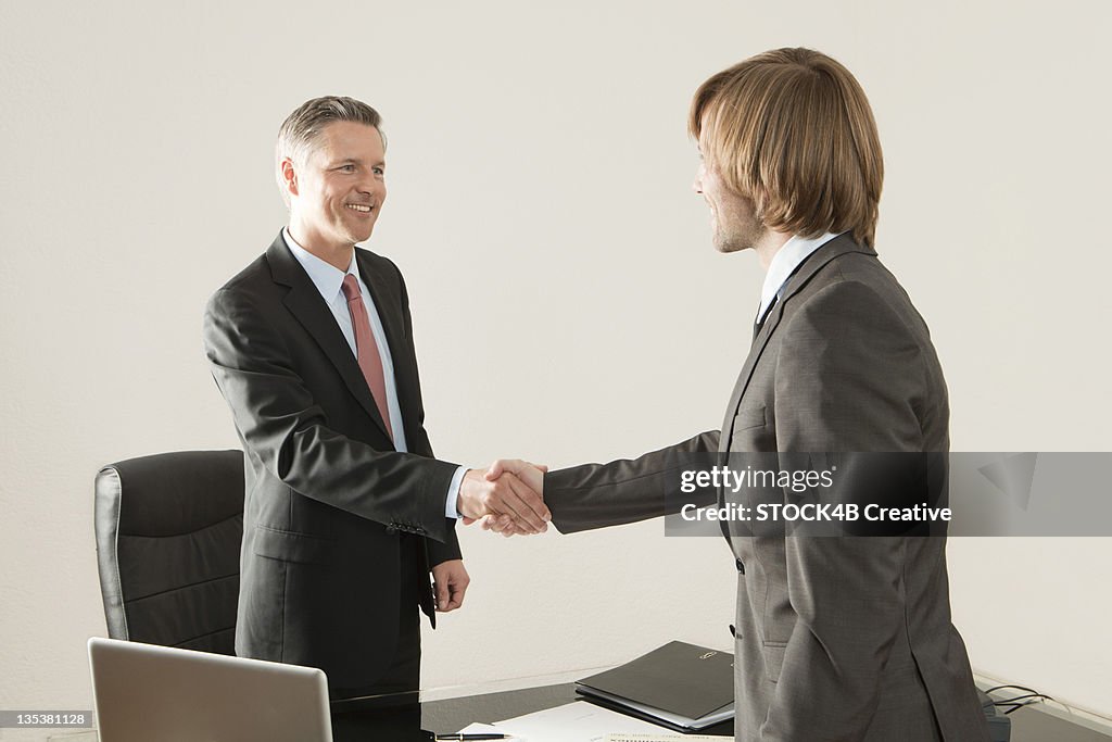 Two businessmen shaking hands in office