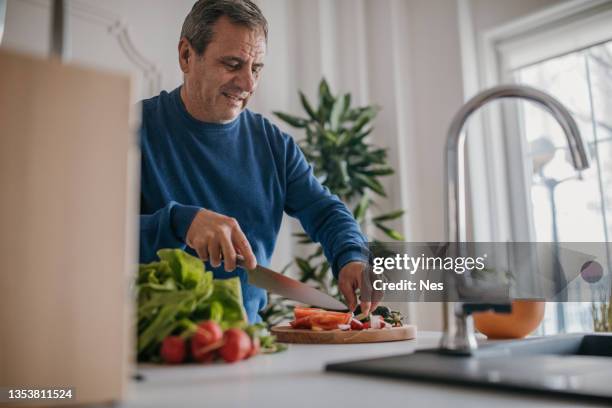 hausmannskost, lächelnder koch beim schneiden von gemüse - hacken essenszubereitung stock-fotos und bilder