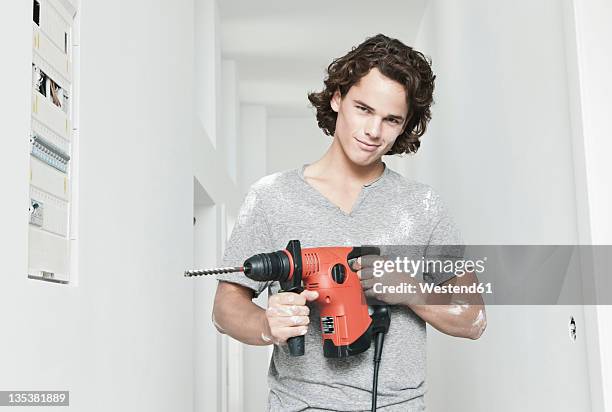 germany, cologne, young man with electric drill in renovating apartment - holding tool stock pictures, royalty-free photos & images