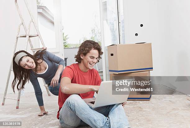 germany, cologne, young couple using laptop in renovating apartment - bent ladder stock pictures, royalty-free photos & images