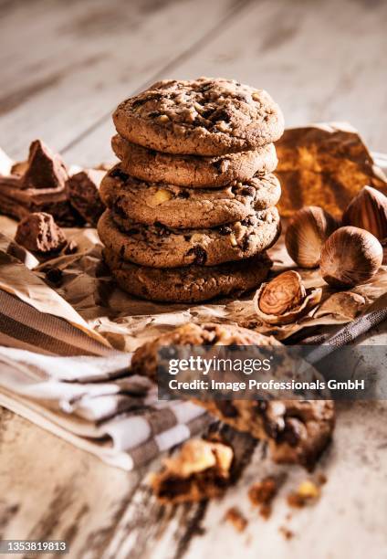 chocolate chip cookies and hazelnuts on a piece of brown paper and a tea towel - brown paper towel stock pictures, royalty-free photos & images