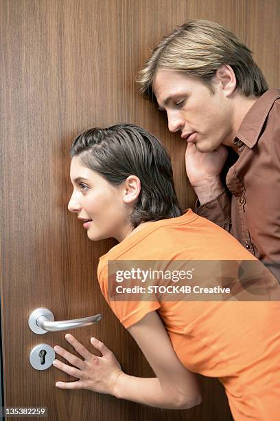man and woman eavesdropping on a door - lauschen stock-fotos und bilder