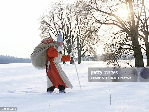 saint nicholas walking through winter landscape - papal stock-fotos und bilder