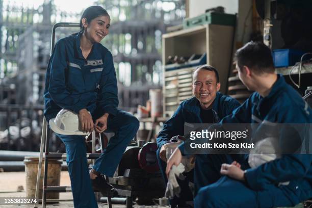 eine gruppe verschiedener asiatischer fabrikarbeiter, die während einer pause ein herzliches gespräch führen - manufacturing occupation stock-fotos und bilder