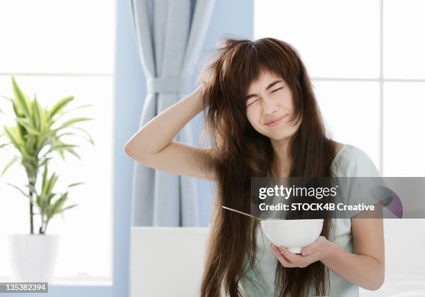 young woman with muesli bowl disheveling her hair - sulking stock pictures, royalty-free photos & images