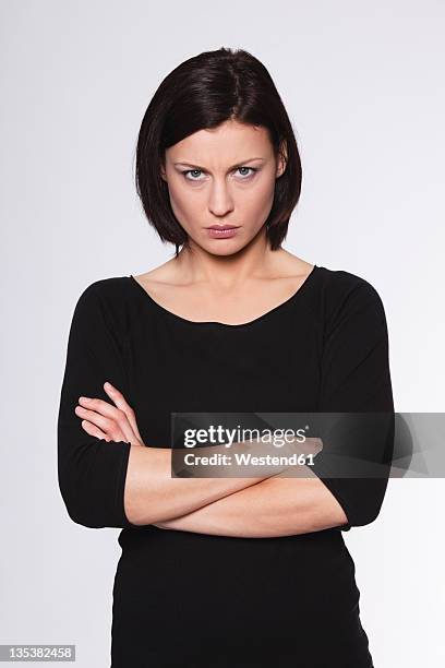 mid adult woman with arms crossed and staring against white background - angry woman stockfoto's en -beelden