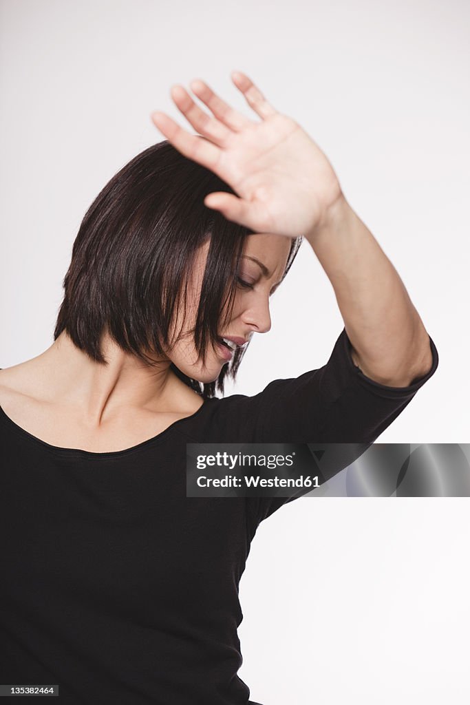 Mid adult woman with stop gesture against white background, close up