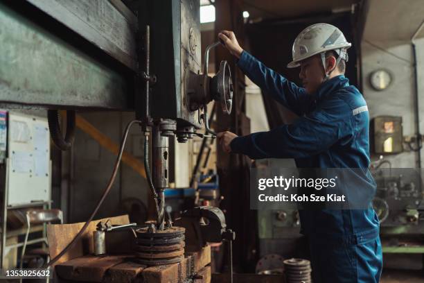 skilled labour worker operating a drilling bit for steel plates - drill bit stockfoto's en -beelden