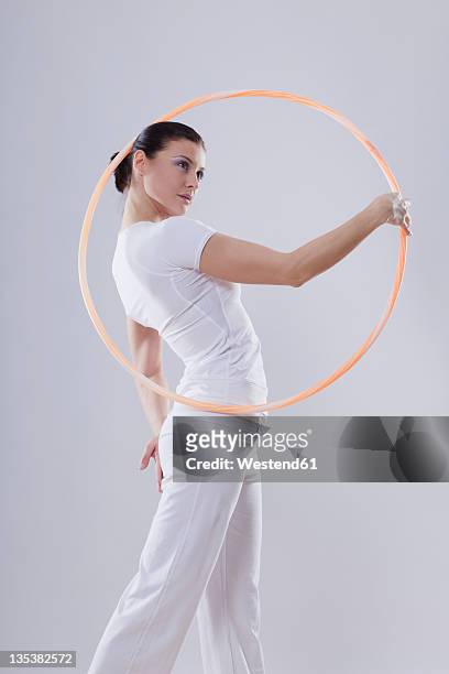 mid adult woman with hoola hoop against white background - hula hoop studio stock pictures, royalty-free photos & images