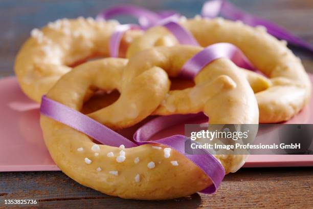 sweet new year's eve pretzels with sugar nibs and a purple ribbon - brezel stock-fotos und bilder