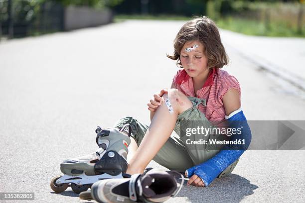 germany, bavaria, wounded girl sitting on road after inline-skating accident - kind gips stock-fotos und bilder