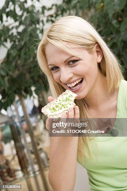 happy young woman eating crisp bread - blond women happy eating stockfoto's en -beelden